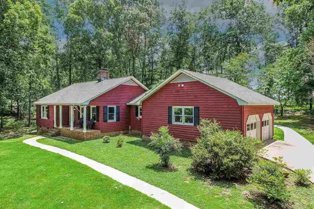 a view of a yard in front of a house with plants and large tree