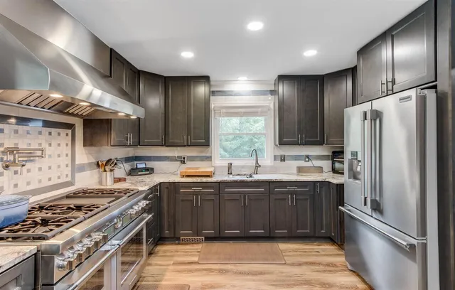 a kitchen with stainless steel appliances granite countertop a stove a sink dishwasher a refrigerator and a oven