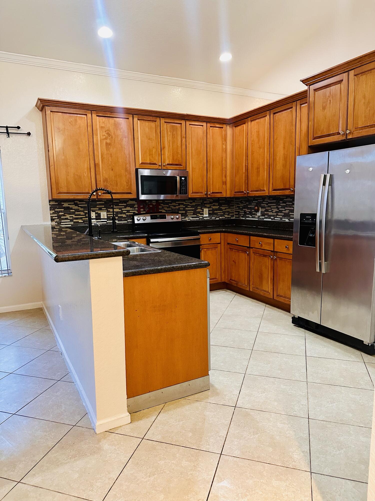 5200 Rising Comet Lane Greenacres, FL 33463 - Photo 11 of 50 a kitchen with stainless steel appliances granite countertop a stove a sink and a microwave