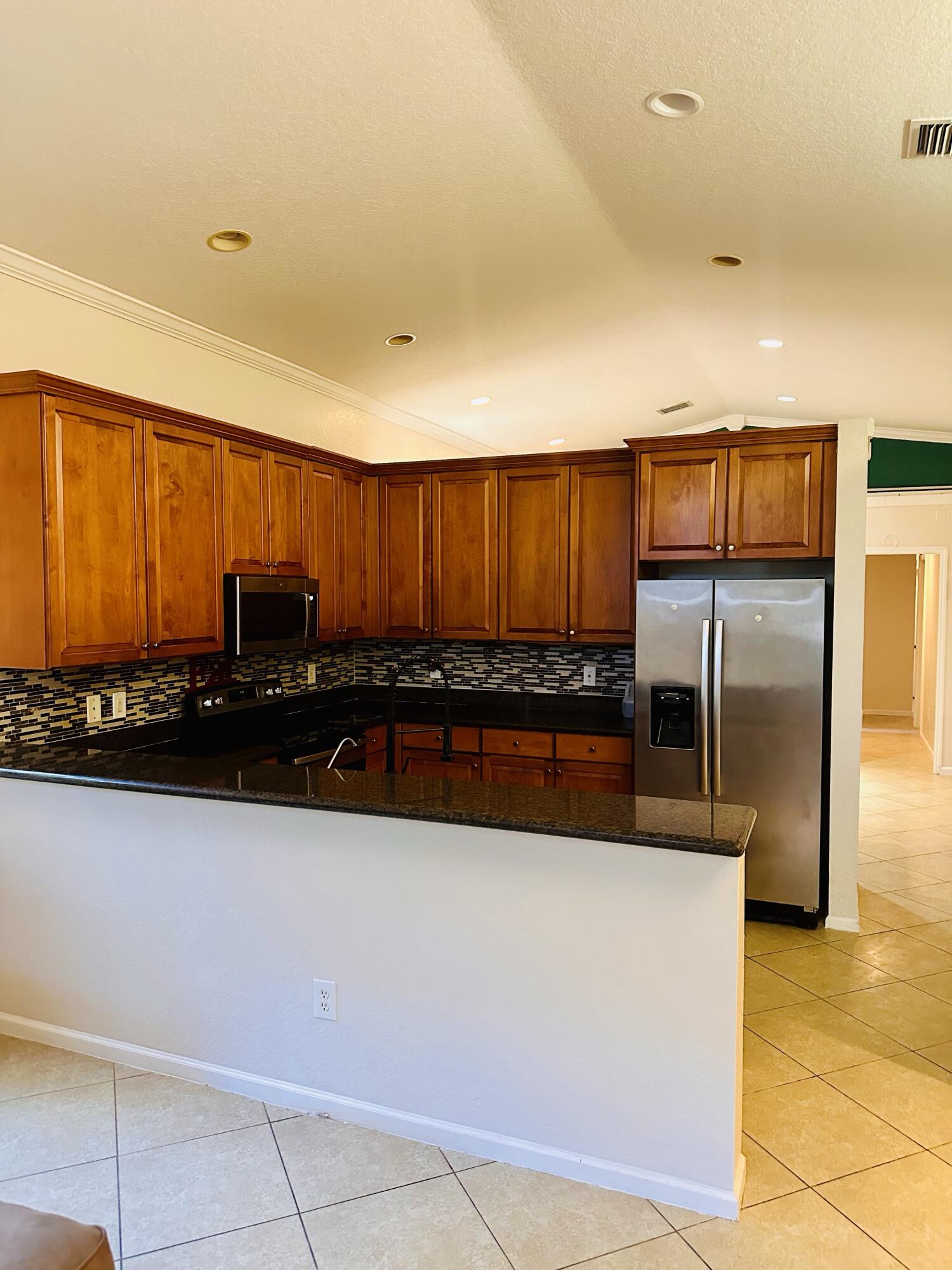 5200 Rising Comet Lane Greenacres, FL 33463 - Photo 12 of 50 a kitchen with stainless steel appliances a refrigerator and a sink