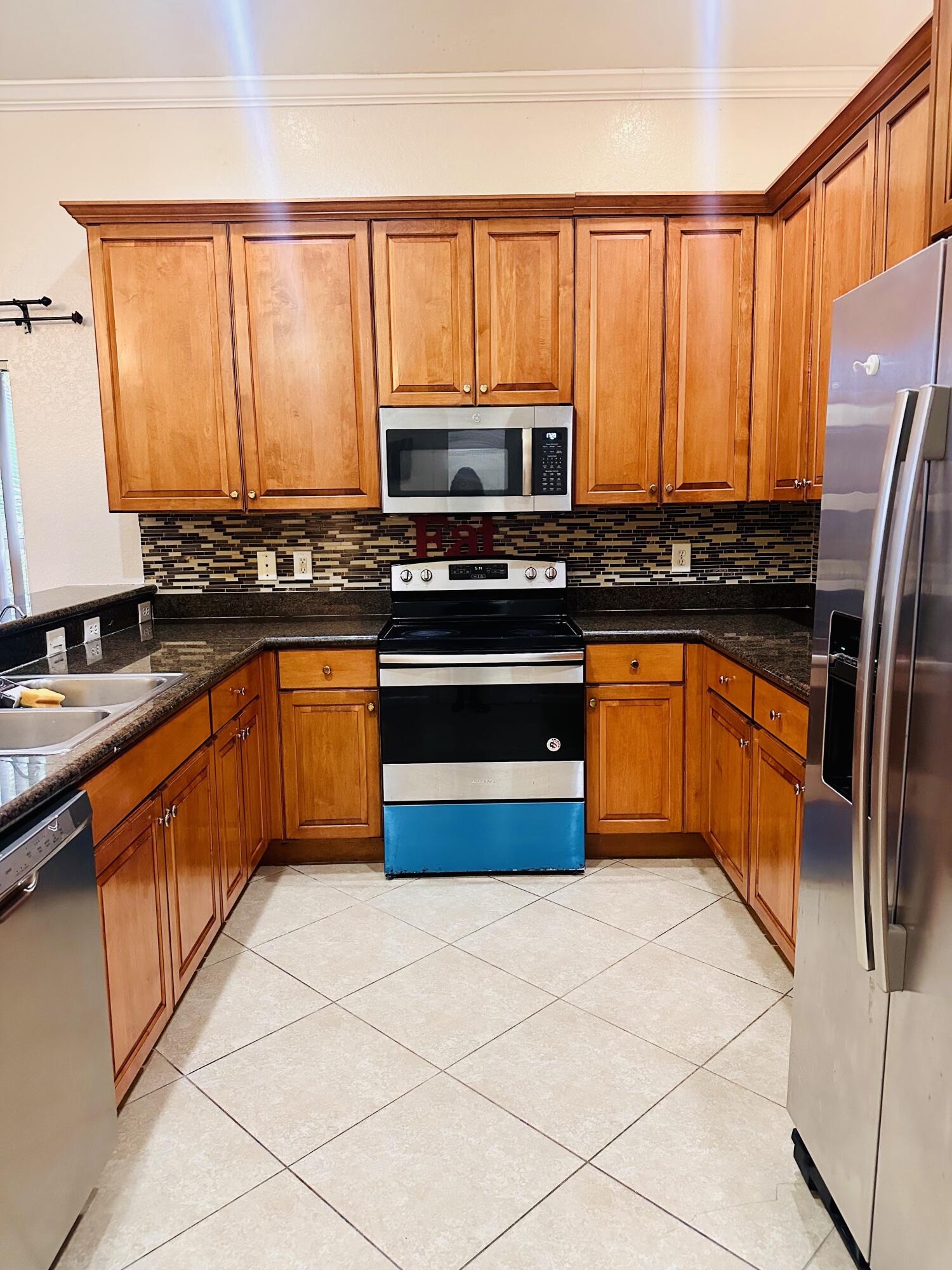 5200 Rising Comet Lane Greenacres, FL 33463 - Photo 10 of 50 a kitchen with stainless steel appliances granite countertop a stove top oven a sink dishwasher and a refrigerator