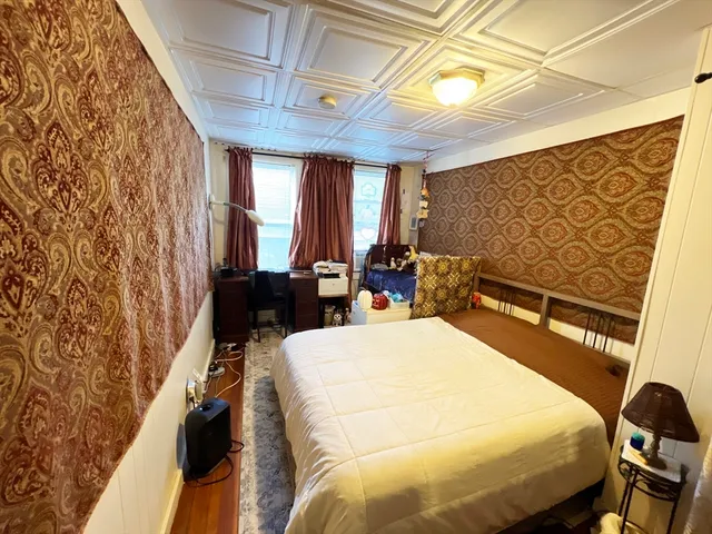 a bedroom with a bed a dresser next to a window