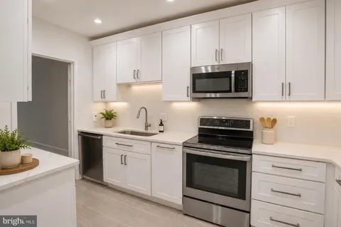 a kitchen with white cabinets and stainless steel appliances