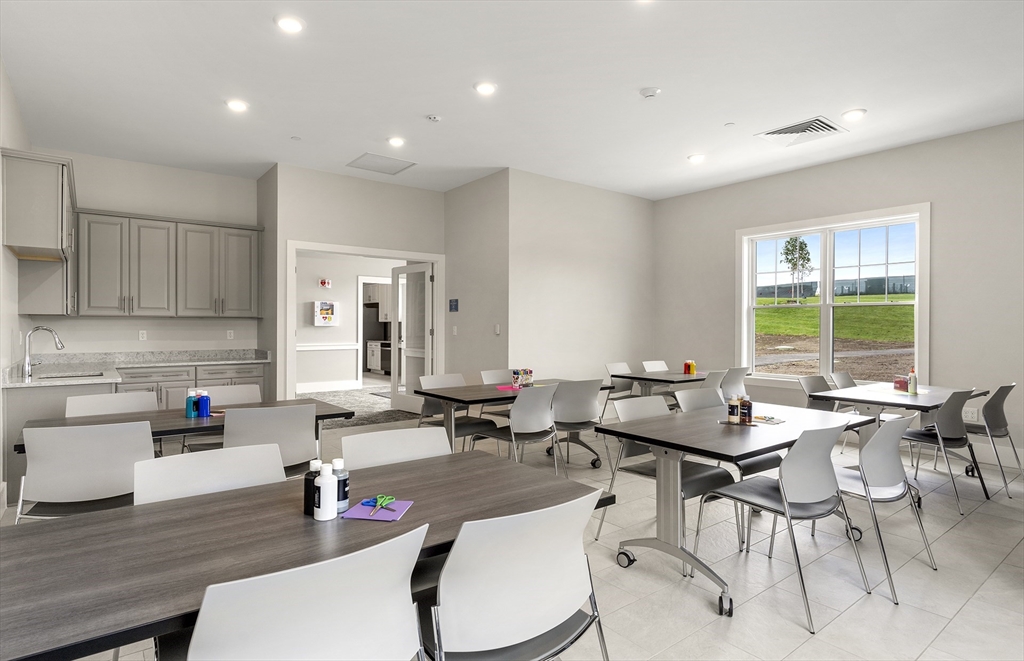 2 Codman Way, Unit 108 Westborough, MA 01581 - Photo 31 of 36 a room with stainless steel appliances a dining table wooden floor and a large window