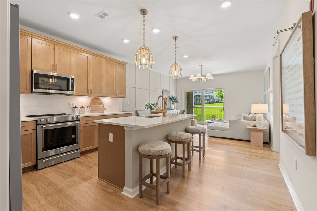 2 Codman Way, Unit 108 Westborough, MA 01581 - Photo 7 of 36 a kitchen with kitchen island granite countertop a stove a sink a dining table and chairs