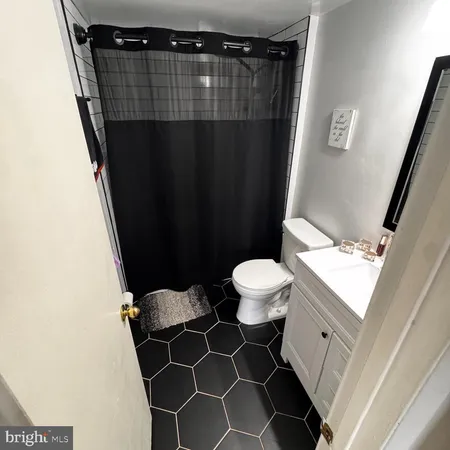 a bathroom with a sink a toilet a shower curtain and a mirror
