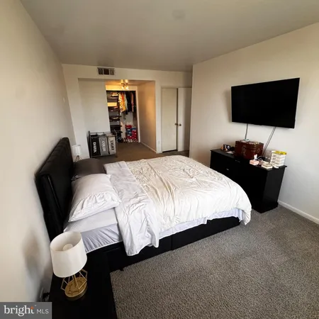 a bedroom with a bed and a flat tv screen on dresser