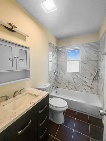 a bathroom with a granite countertop sink toilet and mirror