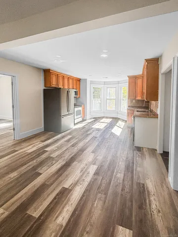 a view of a kitchen with kitchen island wooden floors appliances and cabinets