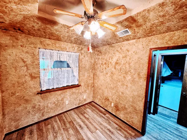 a view of a hallway with wooden floor and a ceiling fan