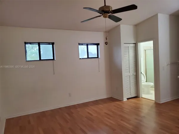 a view of an empty room with wooden floor and a ceiling fan