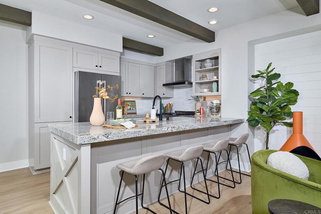 1601 San Remo Place, Unit 101 Encinitas, CA 92024 - Photo 5 of 27 a kitchen with stainless steel appliances kitchen island granite countertop a table chairs in it and wooden floors