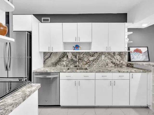 a kitchen with granite countertop a sink and a refrigerator