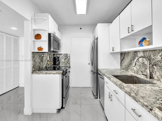 a kitchen with stainless steel appliances granite countertop a sink and a refrigerator