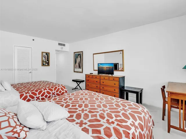 a bedroom with a large bed and a flat tv screen on dresser