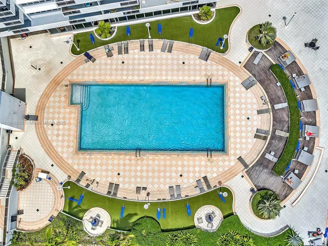 a view of a swimming pool with a lawn chairs and palm trees