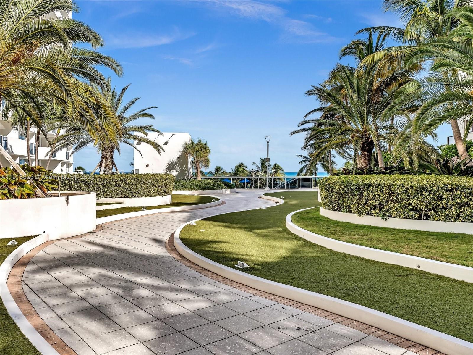 100 Lincoln Road, Unit 710 Miami Beach, FL 33139 - Photo 25 of 36 a view of a swimming pool with a lawn chairs and palm trees