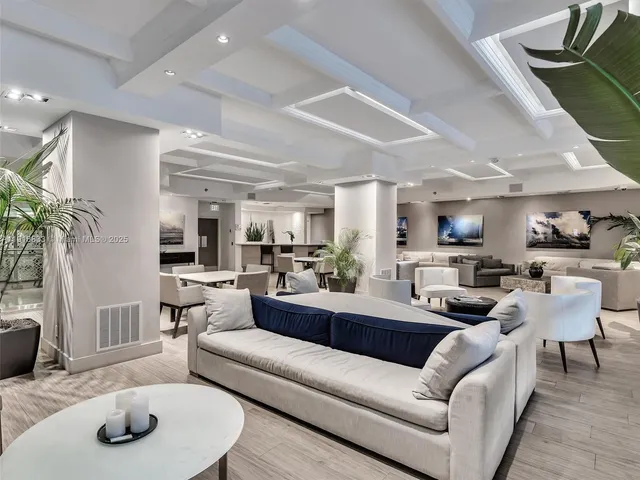 a large white room with bed and a potted plant