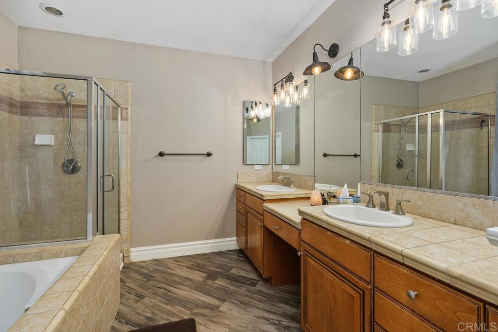 44684 Mumm Street Temecula, CA 92592 - Photo 27 of 51 a spacious bathroom with a granite countertop sink a mirror a shower and a bathtub