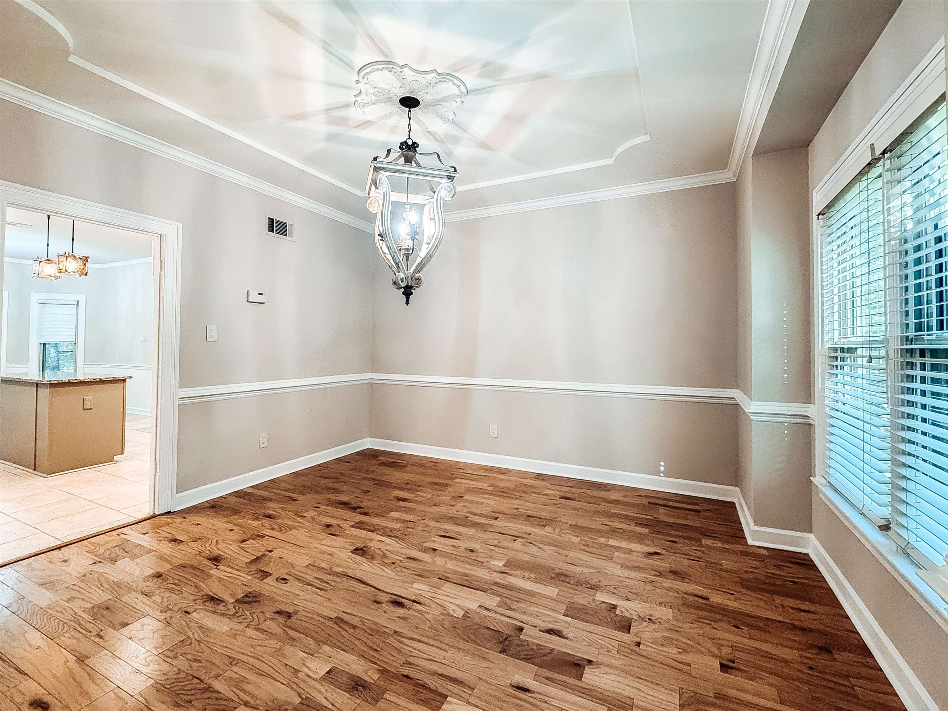 832 South Tree Drive Collierville, TN 38017 - Photo 8 of 40 Formal dining area featuring rich wood-finish flooring, a decorative chandelier with an ornate ceiling medallion, and a tray ceiling