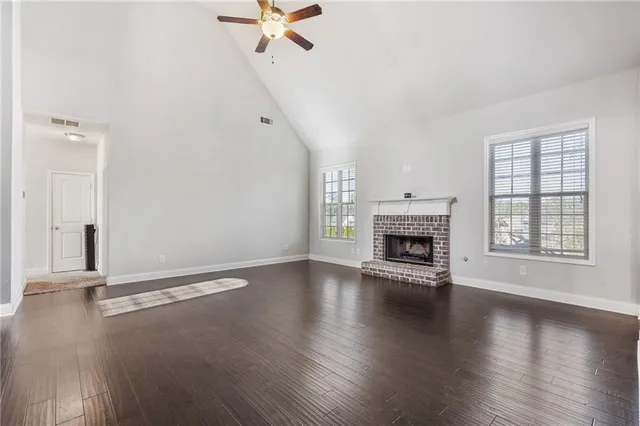 an empty room with wooden floor fireplace and windows