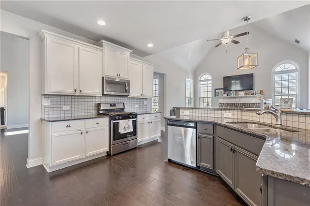 a kitchen with granite countertop white cabinets and stainless steel appliances