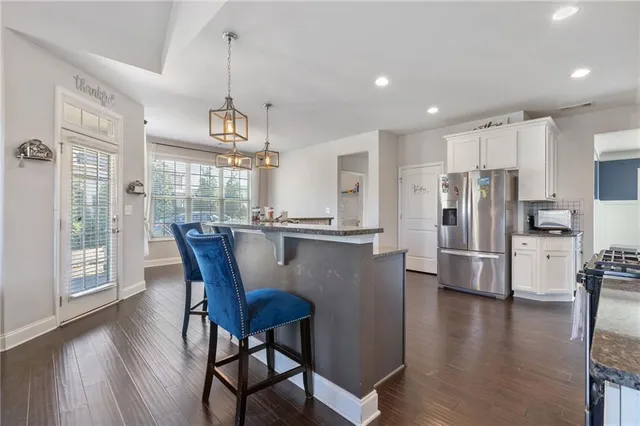 a kitchen with stainless steel appliances granite countertop a dining table chairs refrigerator and a window