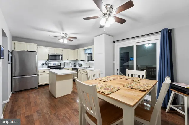 a dining room with stainless steel appliances kitchen island granite countertop a refrigerator a stove a sink dishwasher a dining table and chairs with wooden floor