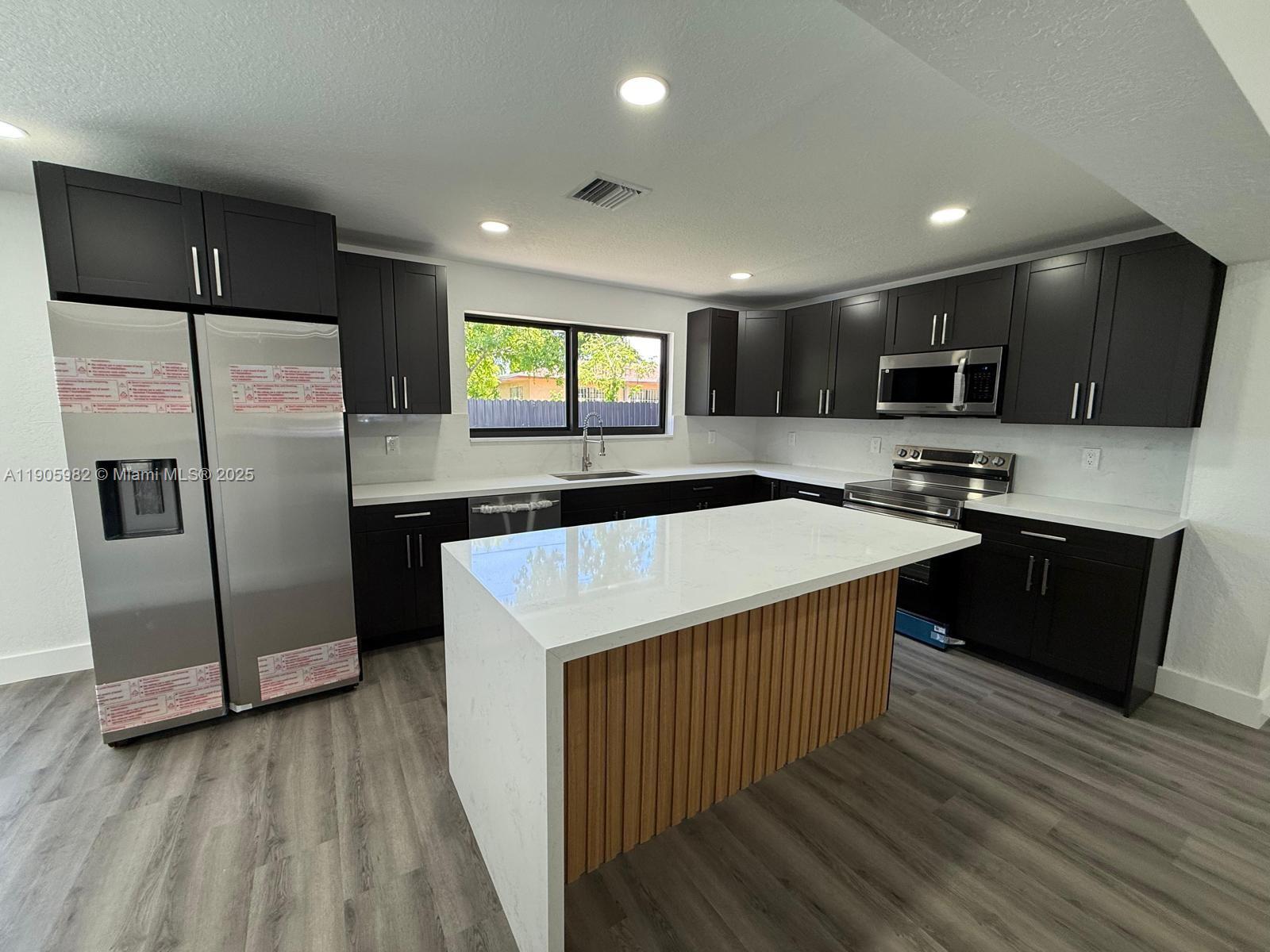 20 Northwest 197th Street Miami Gardens, FL 33169 - Photo 18 of 48 a kitchen with stainless steel appliances granite countertop a refrigerator a sink a stove a microwave and island