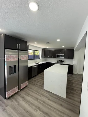 a large kitchen with stainless steel appliances kitchen island a large counter top and a stove top oven