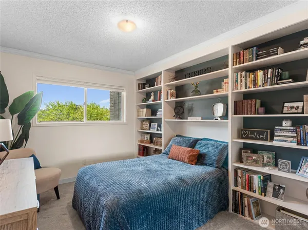 a bedroom with a bed a book shelf and a window