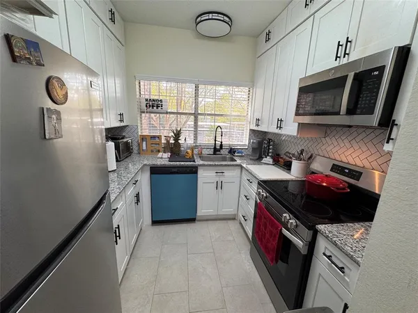 a kitchen with stainless steel appliances a stove a sink dishwasher a microwave oven and a refrigerator