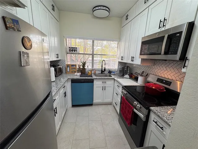 a kitchen with stainless steel appliances a stove a sink dishwasher a microwave oven and a refrigerator