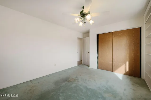 an empty room with a ceiling fan and a window