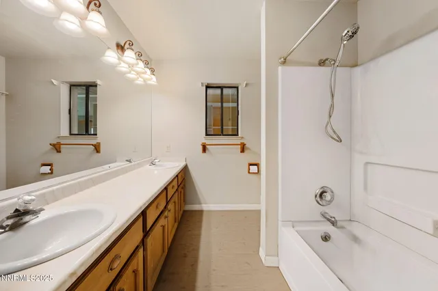 a bathroom with a double vanity sink a large mirror and shower