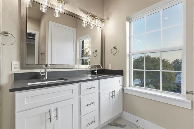 a bathroom with a granite countertop sink mirror and a window
