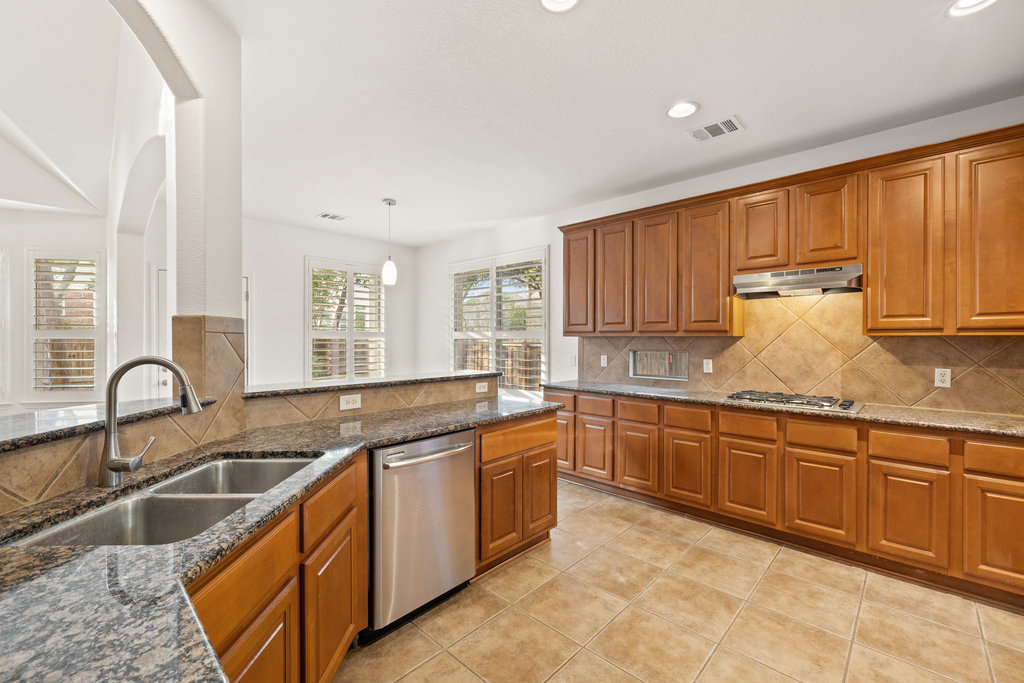 908 Golden Palomino Court Austin, TX 78732 - Photo 18 of 40 a kitchen with granite countertop a sink and cabinets