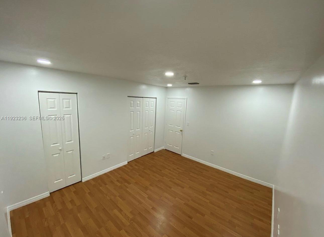 12035 Southwest 14th Street, Unit 103 Miami, FL 33184 - Photo 11 of 17 an empty room with wooden floor and mirror