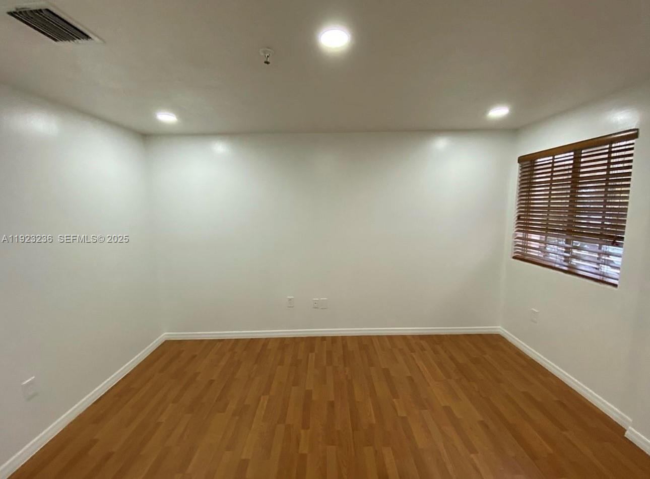 12035 Southwest 14th Street, Unit 103 Miami, FL 33184 - Photo 2 of 17 an empty room with wooden floor and windows