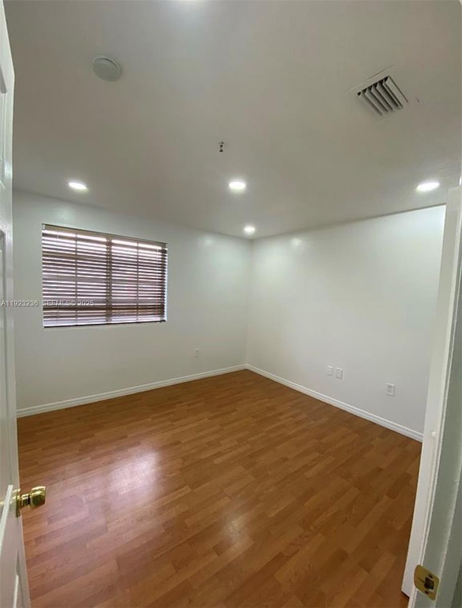 12035 Southwest 14th Street, Unit 103 Miami, FL 33184 - Photo 6 of 17 an empty room with wooden floor and windows