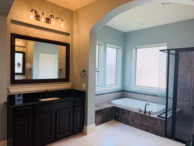 a bathroom with a tub a double vanity sink and a mirror