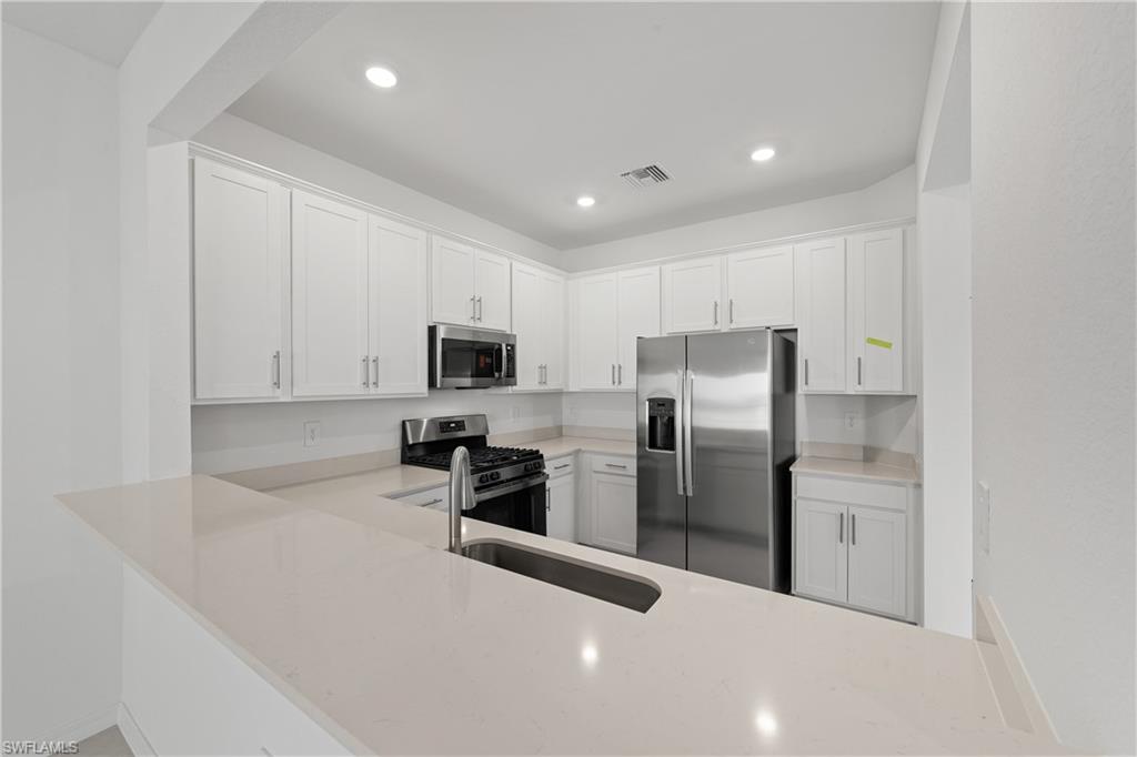 15035 White Pearl Road Babcock Ranch, FL 33982 - Photo 20 of 43 a kitchen with stainless steel appliances a refrigerator sink and microwave