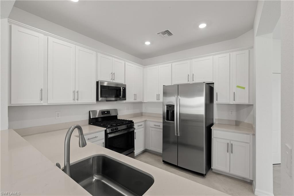 15035 White Pearl Road Babcock Ranch, FL 33982 - Photo 22 of 43 a kitchen with stainless steel appliances granite countertop a refrigerator a stove a sink and white cabinets