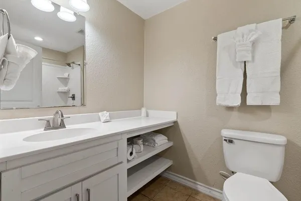 a bathroom with a granite countertop toilet sink and mirror