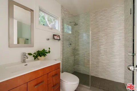 a bathroom with a sink a toilet a shower and a mirror