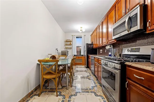 a kitchen with stainless steel appliances granite countertop a stove top oven a sink a dining table and chairs