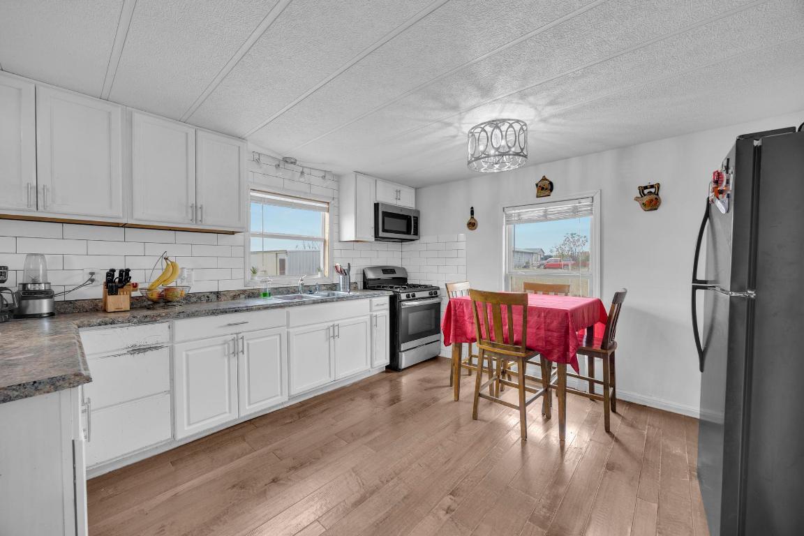 106 Cloudberry Lane Elgin, TX 78621 - Photo 11 of 33 a kitchen with stainless steel appliances granite countertop a refrigerator a stove a sink dishwasher and white cabinets with wooden floor