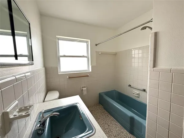 a bathroom with a granite countertop sink a toilet and tub