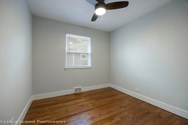 an empty room with wooden floor cabinet and windows