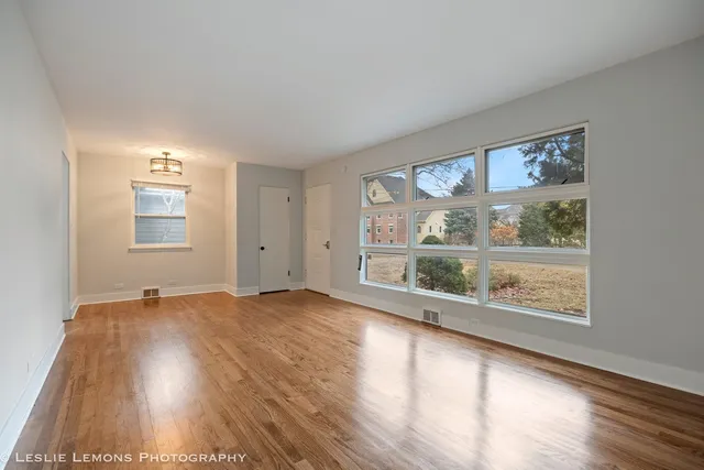 a view of an empty room with a window and wooden floor